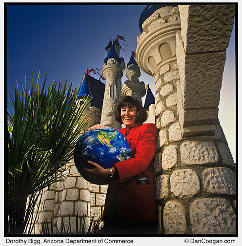 Dorothy Bigg, Director, International Trade and Investment Division, AZ Department of Commerce, hugging a globe, standing in front of a disney-like castle