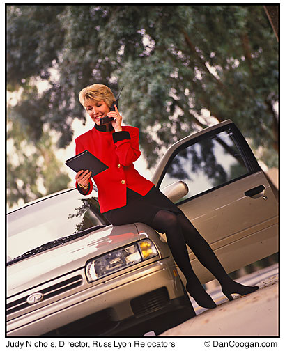Judy Nichols, Director of Corporate Business Development, Russ Lyon Relocators talking on cell phone sitting on her car
