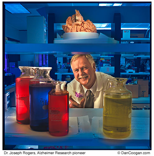 Dr. Joseph Rogers, Research pioneer in Alzheimer and other degenerative brain ailments, holds a slide with brain tissue with a brain model above him